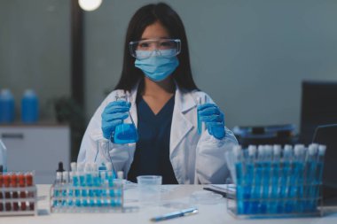 Kendini adamış bir grup bilim adamı tıbbi laboratuvarda kimyasal deney yapıyor. Aşı ilacı veya antibiyotik geliştirmek için pipetten deney tüpüne kesin miktarda sıvı döküyorlar. Neoterik