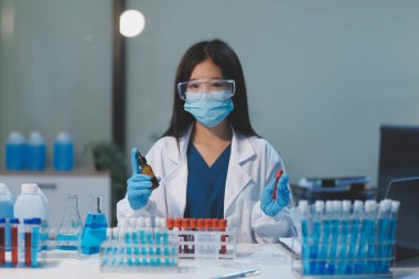 Kendini adamış bir grup bilim adamı tıbbi laboratuvarda kimyasal deney yapıyor. Aşı ilacı veya antibiyotik geliştirmek için pipetten deney tüpüne kesin miktarda sıvı döküyorlar. Neoterik