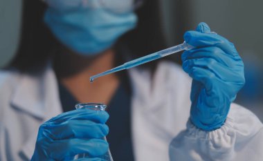 Kendini adamış bir grup bilim adamı tıbbi laboratuvarda kimyasal deney yapıyor. Aşı ilacı veya antibiyotik geliştirmek için pipetten deney tüpüne kesin miktarda sıvı döküyorlar. Neoterik