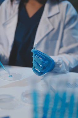 Kendini adamış bir grup bilim adamı tıbbi laboratuvarda kimyasal deney yapıyor. Aşı ilacı veya antibiyotik geliştirmek için pipetten deney tüpüne kesin miktarda sıvı döküyorlar. Neoterik