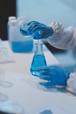 Kendini adamış bir grup bilim adamı tıbbi laboratuvarda kimyasal deney yapıyor. Aşı ilacı veya antibiyotik geliştirmek için pipetten deney tüpüne kesin miktarda sıvı döküyorlar. Neoterik