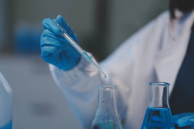 Kendini adamış bir grup bilim adamı tıbbi laboratuvarda kimyasal deney yapıyor. Aşı ilacı veya antibiyotik geliştirmek için pipetten deney tüpüne kesin miktarda sıvı döküyorlar. Neoterik