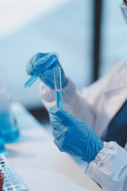 Kendini adamış bir grup bilim adamı tıbbi laboratuvarda kimyasal deney yapıyor. Aşı ilacı veya antibiyotik geliştirmek için pipetten deney tüpüne kesin miktarda sıvı döküyorlar. Neoterik