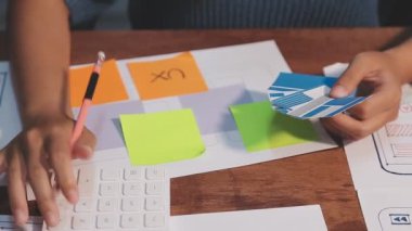 Genç iş kadını tasarımcı akıllı telefon kullanıyor ve ofiste çalışıyor.