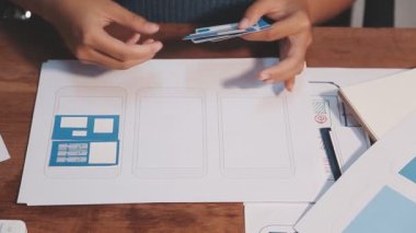 kadın Web UX tasarımcısı masadaki mobil cevap veren web sitesi üzerinde çalışıyor