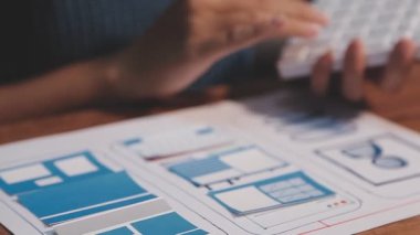 kadın Web UX tasarımcısı masadaki mobil cevap veren web sitesi üzerinde çalışıyor