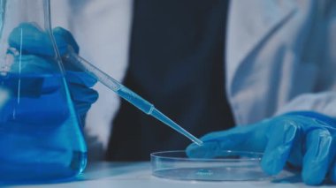 Laboratuvarda elinde sıvı olan bir deney tüpü tutan bilim adamı.