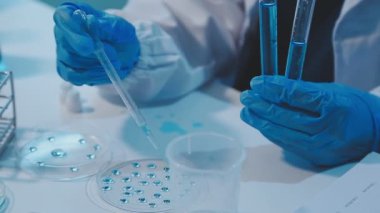 Laboratuvar asistanı test tüpünü sıvı ile tutuyor.
