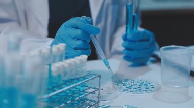 Koruyucu gözlüklü bilim adamı test tüpleriyle çalışıyor.