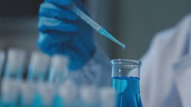 Kapat. Laboratuvarda bir pipetle deney tüpü tutan bilim adamı..