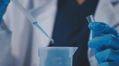 Koruyucu eldivenler içinde laboratuvar asistanı ve sıvı ile test tüpü. laboratuvar araştırma konsepti.