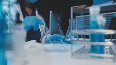 Laboratuvarda sıvı ve pipetle cam tutan bilim adamı..