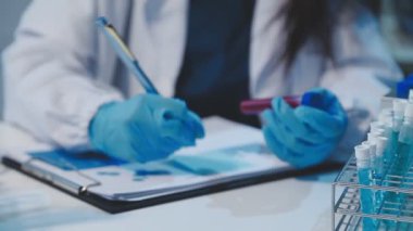 Laboratuvar asistanı laboratuarda test tüplerini sıvı ile tutuyor..