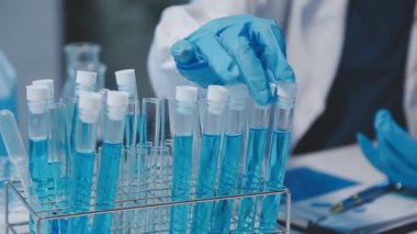 Genç kadın bilim adamı son teknoloji bir laboratuvarda kimyasal sıvılarla deneyler yapıyor..