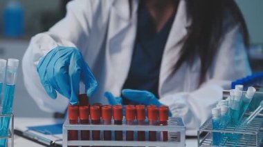Laboratuvarda üzerinde kan örnekleri olan test tüpü tutan üniformalı bilim adamlarının yakınına..