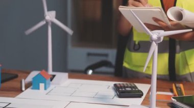 Üniformalı ve kasklı kadın mimar ofiste planlarla çalışıyor..