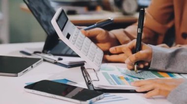 Modern ofisteki masada evrak işleriyle uğraşırken dizüstü bilgisayarda çalışan kadınların yakın plan fotoğrafları.