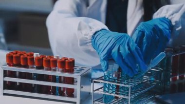 Kadın bilim adamının yakın plan görüntüsü modern laboratuardaki test tüplerini inceliyor.