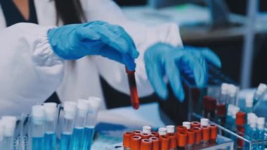 Kadın bilim adamının yakın plan görüntüsü modern laboratuardaki test tüplerini inceliyor.