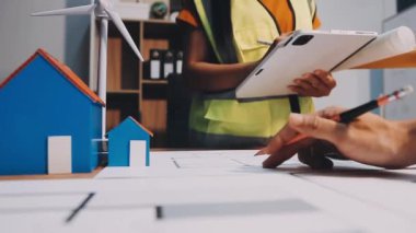 Ofiste çalışan genç bir kadın mühendis, planlarla çalışan bir mimar..