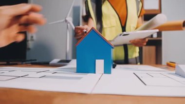 Taslak üzerinde ev modeli olan bir emlakçı, yakın plan. Emlakçı ya da menajer