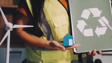 Masasında kağıt geri dönüşüm tabelası ve geri dönüşüm tabelası olan yeşil gömlekli kadın, ekoloji, çevre koruma ve ekoloji kavramı.