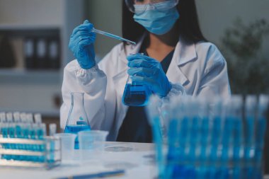 Kendini adamış bir grup bilim adamı tıbbi laboratuvarda kimyasal deney yapıyor. Aşı ilacı veya antibiyotik geliştirmek için pipetten deney tüpüne kesin miktarda sıvı döküyorlar. Neoterik