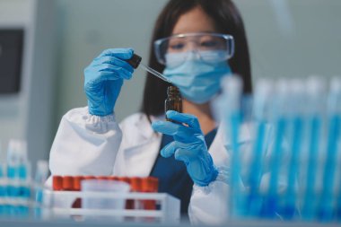 Kendini adamış bir grup bilim adamı tıbbi laboratuvarda kimyasal deney yapıyor. Aşı ilacı veya antibiyotik geliştirmek için pipetten deney tüpüne kesin miktarda sıvı döküyorlar. Neoterik