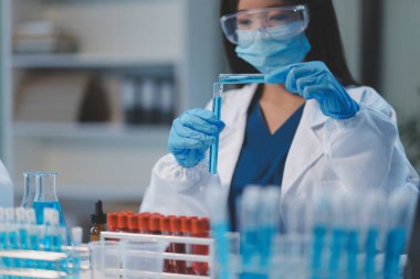 Kendini adamış bir grup bilim adamı tıbbi laboratuvarda kimyasal deney yapıyor. Aşı ilacı veya antibiyotik geliştirmek için pipetten deney tüpüne kesin miktarda sıvı döküyorlar. Neoterik