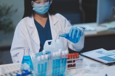 Kendini adamış bir grup bilim adamı tıbbi laboratuvarda kimyasal deney yapıyor. Aşı ilacı veya antibiyotik geliştirmek için pipetten deney tüpüne kesin miktarda sıvı döküyorlar. Neoterik