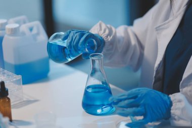 Kendini adamış bir grup bilim adamı tıbbi laboratuvarda kimyasal deney yapıyor. Aşı ilacı veya antibiyotik geliştirmek için pipetten deney tüpüne kesin miktarda sıvı döküyorlar. Neoterik