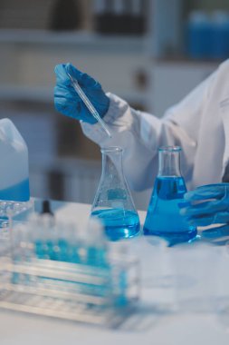 Kendini adamış bir grup bilim adamı tıbbi laboratuvarda kimyasal deney yapıyor. Aşı ilacı veya antibiyotik geliştirmek için pipetten deney tüpüne kesin miktarda sıvı döküyorlar. Neoterik