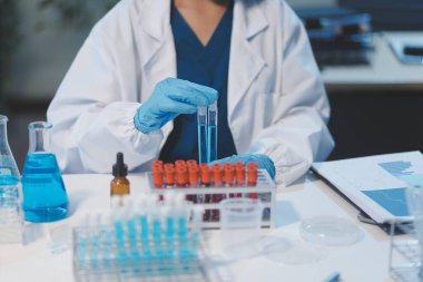 Kendini adamış bir grup bilim adamı tıbbi laboratuvarda kimyasal deney yapıyor. Aşı ilacı veya antibiyotik geliştirmek için pipetten deney tüpüne kesin miktarda sıvı döküyorlar. Neoterik