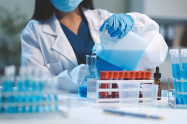 Kendini adamış bir grup bilim adamı tıbbi laboratuvarda kimyasal deney yapıyor. Aşı ilacı veya antibiyotik geliştirmek için pipetten deney tüpüne kesin miktarda sıvı döküyorlar. Neoterik