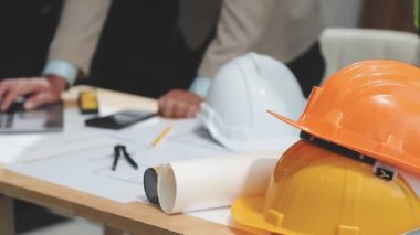 Ahşap zemin üzerine planlar, miğfer, miğfer ve planlar üzerinde çalışan mühendis..