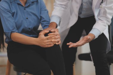 Klinikteki küçük hastanın bacağını muayene eden profesyonel bir ortopedist. Fizyoterapideki hasta terapistiyle fiziksel egzersiz yapıyor.