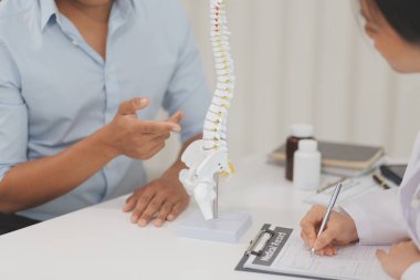 Ortopedistler dijital tablet tutuyor ve mankeni işaret ediyorlar. Osteoporoz, sırt ağrısı, bel, kiropraktik ve sağlık kavramı.