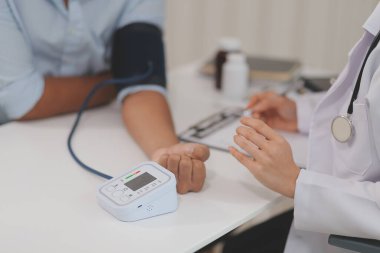 Doktor kadın nabız sayacını hastanın basıncını ölçmek için kullanıyor. Tıbbi kontrol konsepti..