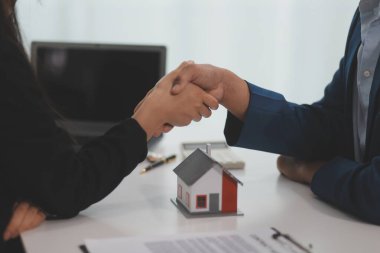 Emlak acentesi kontrat imzalandıktan sonra müşteriyle tokalaşıyor