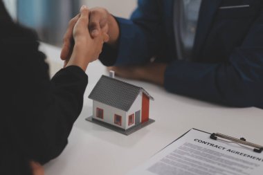 Emlak acentesi kontrat imzalandıktan sonra müşteriyle tokalaşıyor