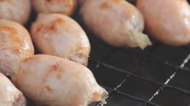 Şişler üzerinde ızgara yapılan ve yanında sosis kızaran tavuk satayının detaylı görüntüsü..