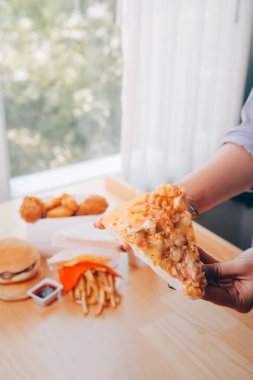 Restoranda pizza dilimi tutan bir kadın resmi.