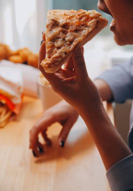 Restoranda pizza dilimi tutan bir kadın resmi.