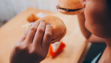 Binge eating disorder concept with woman eating fast food burger, fired chicken , donuts and desserts clipart