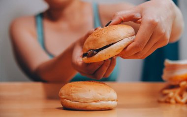 Binge eating disorder concept with woman eating fast food burger, fired chicken , donuts and desserts clipart