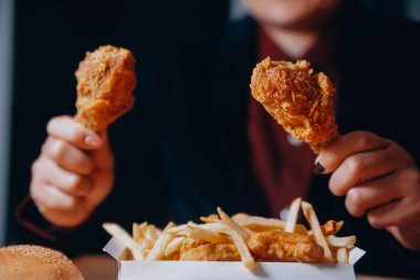 Odaklan kadın. Elin kızarmış tavuğu yemek için tutuyor. Fast food konsepti olan bir kız.