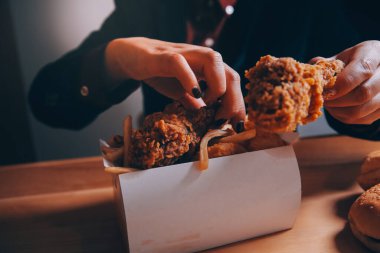 Odaklan kadın. Elin kızarmış tavuğu yemek için tutuyor. Fast food konsepti olan bir kız.