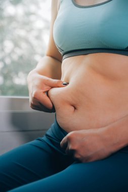 Şişman kadın, şişko, obez kadın el ele tutuşan ölçü bandıyla göbek yağı, kadın diyeti yaşam tarzı konsepti
