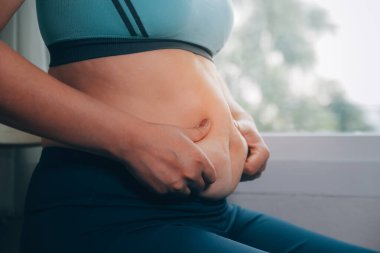 Şişman kadın, şişko, obez kadın el ele tutuşan ölçü bandıyla göbek yağı, kadın diyeti yaşam tarzı konsepti