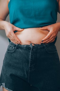 Şişman kadın, şişko, obez kadın el ele tutuşan ölçü bandıyla göbek yağı, kadın diyeti yaşam tarzı konsepti